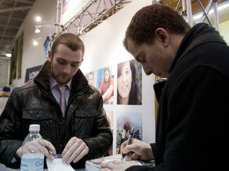 Belleville Bulls' Michael Curtis and Brent Larmer sign autographs at the Loyalist College booth during Loyalist College Night at the Yardmen Arena.
