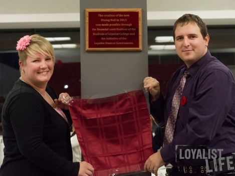 Loyalist Board of Governors Student Representative and Enactus President Elizabeth Kryschuk (left) and Student Government Past President (2012-13) Chris Detering unveil a plaque of recognition in the Dining Hall. (Photo by Carla Antonio.)